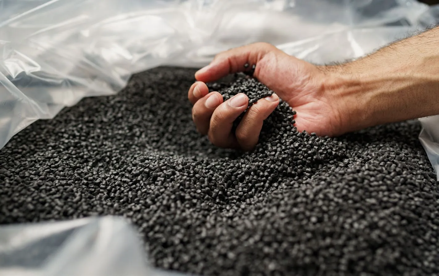 Hand holding recycled polymer pellets
